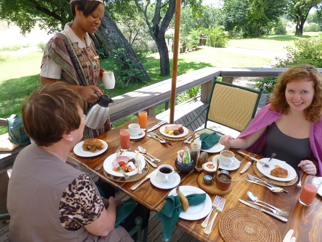Every meal was scrumptuous. Here, we're able to eat breakfast on a deck that overlooks the Sand River (Marnie at left, Brianna at right). We saw a couple of animals stroll across the adjacent lawn. Photo by FG.
